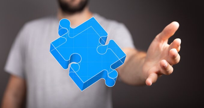 Abstract image of a hand reaching for a 3D blue puzzle piece. Solution, connection, teamwork concept.