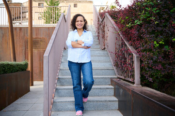 Friendly Woman Descending Outdoor Staircase in Jeans and Light Blue Shirt - Casual Portrait of Confidence and Everyday Style
