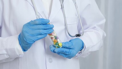 Doctor with stethoscope holding colorful medicine pills and capsules in gloved hands for medical treatment - Powered by Adobe