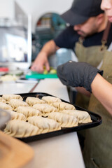 Chefs preparing asian dumplings, making fresh gyoza by hand, showcasing traditional cooking methods in a professional kitchen