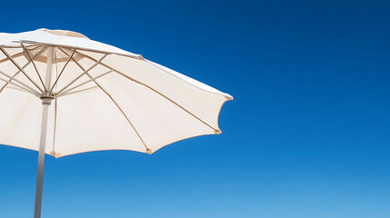Obraz premium Sunshade against a cloudless sky. The pale canopy blocks direct sunlight. A simple support structure contrasts with the intense blue sky, conveying warm relaxation.