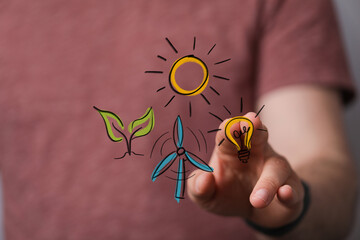 Person's hand interacts with holographic symbols of sustainable energy: sun, wind turbine, plant, and light bulb. Illustrates eco-friendly innov