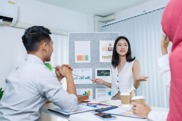 A woman and a man are talking in front of a white board with a picture on it. The woman is pointing at the picture and the man is looking at her
