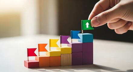 Hand placing green arrow block on colorful ascending stair-step blocks symbolizing growth