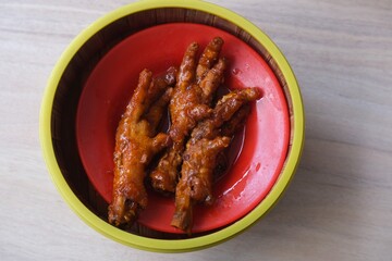 A serving of braised chicken feet, a popular dish in Chinese dim sum, presented in a red dish within a bamboo steamer.