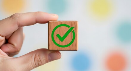 Hand holding wooden block with green checkmark symbol signifying success and approval