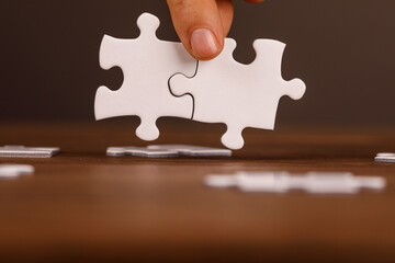A hand placing a puzzle piece to connect with another. Representing teamwork, problem-solving, and the completion of a task. Conceptual image fo