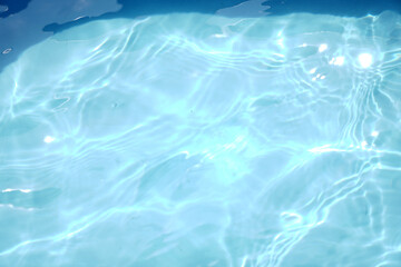 A serene, top-down view of shimmering blue water with sunlit ripples, creating a beautiful abstract...