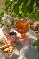 Berry jam and coffee on a table with a tablecloth in a summer garden