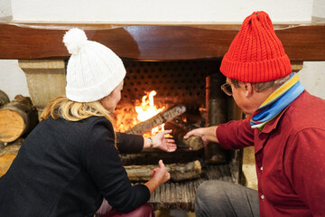 Couple in winter hats enjoying the fire