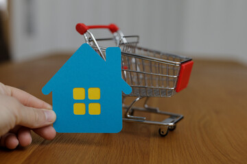 Conceptual image of home buying and real estate, with a miniature house and a shopping cart, suggesting the idea of acquiring property, home fin