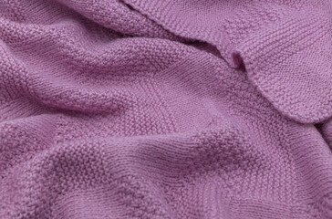 Purple knit fabric as a background. Wool knit texture. Purple knitted fabric surface with soft folds. Textile material for design. Purple knitted texture. 