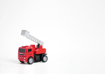 A red toy fire truck with an extended ladder, positioned on a clean white background. The clean, minimalist shot highlights childhood, play, and rescue themes.