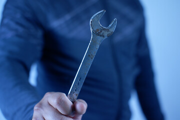 A person is holding a wrench in their hand. firmly grips silver double-ended wrench for tighteninga worker, builder, repairman, handyman, holding wrench. Workshop equipment