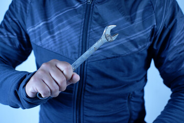 A person is holding a wrench in their hand. firmly grips silver double-ended wrench for tighteninga worker, builder, repairman, handyman, holding wrench. Workshop equipment