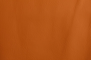 Close-up shot of an orange leather texture, perfect for backgrounds. Reveals intricate grain details, representing comfort, classic design, and
