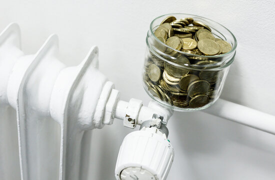 Financial concept with coins in a jar placed on a radiator, symbolizing savings, energy costs, and home heating. Representing saving money on he