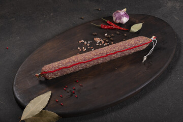 Dry-cured and smoked sausage on a dark background