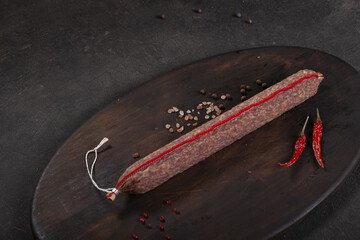 Dry-cured and smoked sausage on a dark background