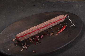 Dry-cured and smoked sausage on a dark background