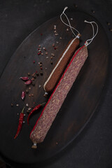 Dry-cured and smoked sausage on a dark background