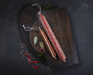 Dry-cured and smoked sausage on a dark background
