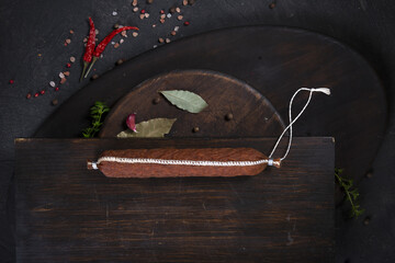 Dry-cured and smoked sausage on a dark background