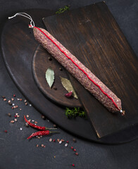Dry-cured and smoked sausage on a dark background