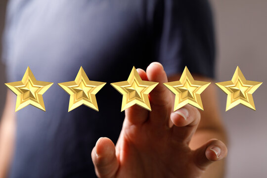 A hand touching five golden stars, symbolizing a perfect rating, ideal for customer feedback, reviews, and business performance. Represents sati