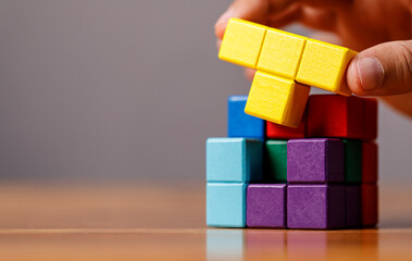 Person assembling a cube puzzle with colorful blocks. Concepts of problem solving, teamwork,...