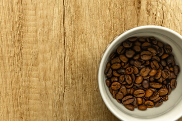 Rising Coffee Prices Concept with Cup and Spilled Coffee Beans on Wooden Table