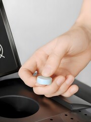 Hand Inserting Blue Purification Tablet Cartridge into Sleek Water Dispenser Unit