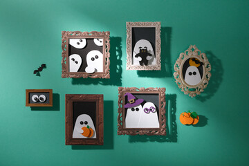 Handmade Halloween decorations. A turquoise wall with portraits of ghosts with pumpkins, cats, and bats. Paper arts.