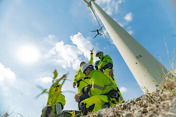 Engineers use a drone to inspect a wind turbine on a bright day, showcasing the integration of technology in renewable energy projects. teamwork, wind power, and modern engineering solutions.
