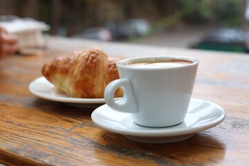 Aromatic coffee and tasty croissant on wooden table, closeup