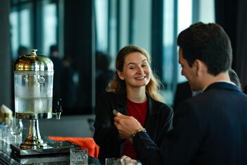 Smiling businesswoman talking with colleague over drinks in elegant bar setting, reflecting teamwork, trust, and social interaction in a professional urban environment.