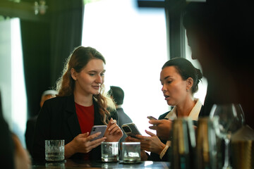 Business team connecting through digital technology while enjoying drinks at luxury rooftop bar, reflecting networking, collaboration, and seamless cashless lifestyle.
