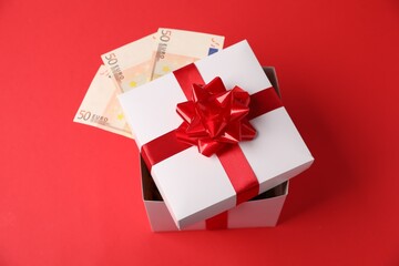 Gift box with euro banknotes on red background