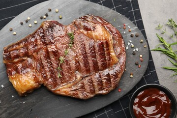 Delicious grilled beef steak with herbs, spices and ketchup on grey textured table, flat lay