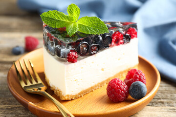 Piece of delicious cheesecake with berries and mint on wooden table, closeup