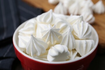 Delicious meringue cookies in bowl on table, closeup