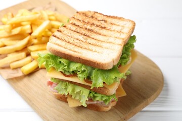 Tasty sandwich served with french fries on white wooden table, closeup