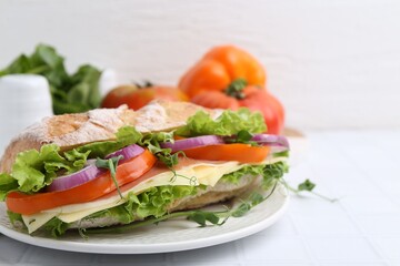 Delicious ciabatta sandwich with prosciutto, cheese and vegetables on white tiled table, closeup. Space for text