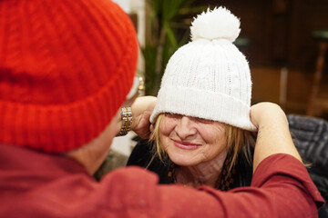 Husband Helping Wife with Winter Hat at Home
