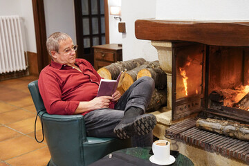 Mature man Reading by the Fireplace in winter