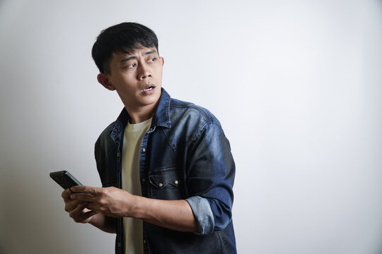 Man Holding Smartphone Looking Worriedly Off-Camera