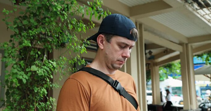 Casual urban male in cap observing cityscape outdoors, reflecting modern lifestyle, street style, relaxation. Urban exploration, contemporary fashion.