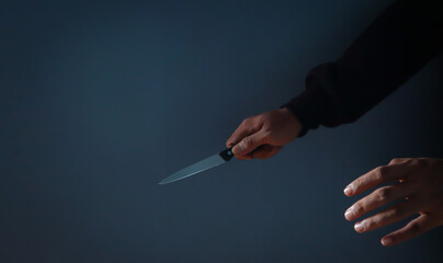 Man's hand holds a knife on dark background. topics of violence and murder. thief, killer, rapist,...