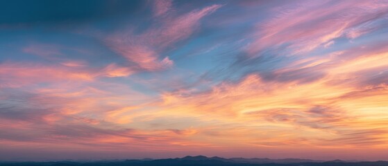 Fototapeta premium Panoramic sunset sky with warm golden, orange, and pink tones blending into soft blue across a wide horizon.