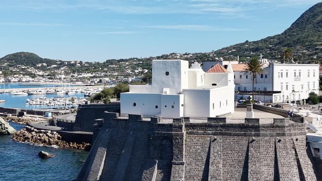 Beautiful white church Santa Maria del Soccorso
in Forio of Ischia island in Italy coastal drone shot with deep blue sea waves, cliffs and sunny weather. 